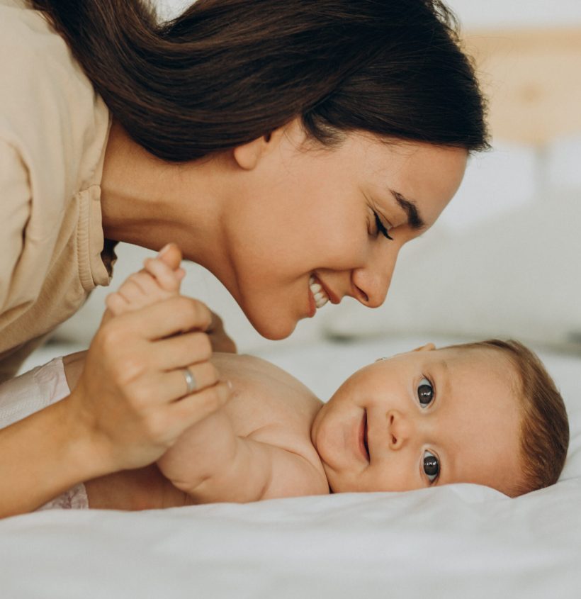 Mother with baby daughter lying on bed