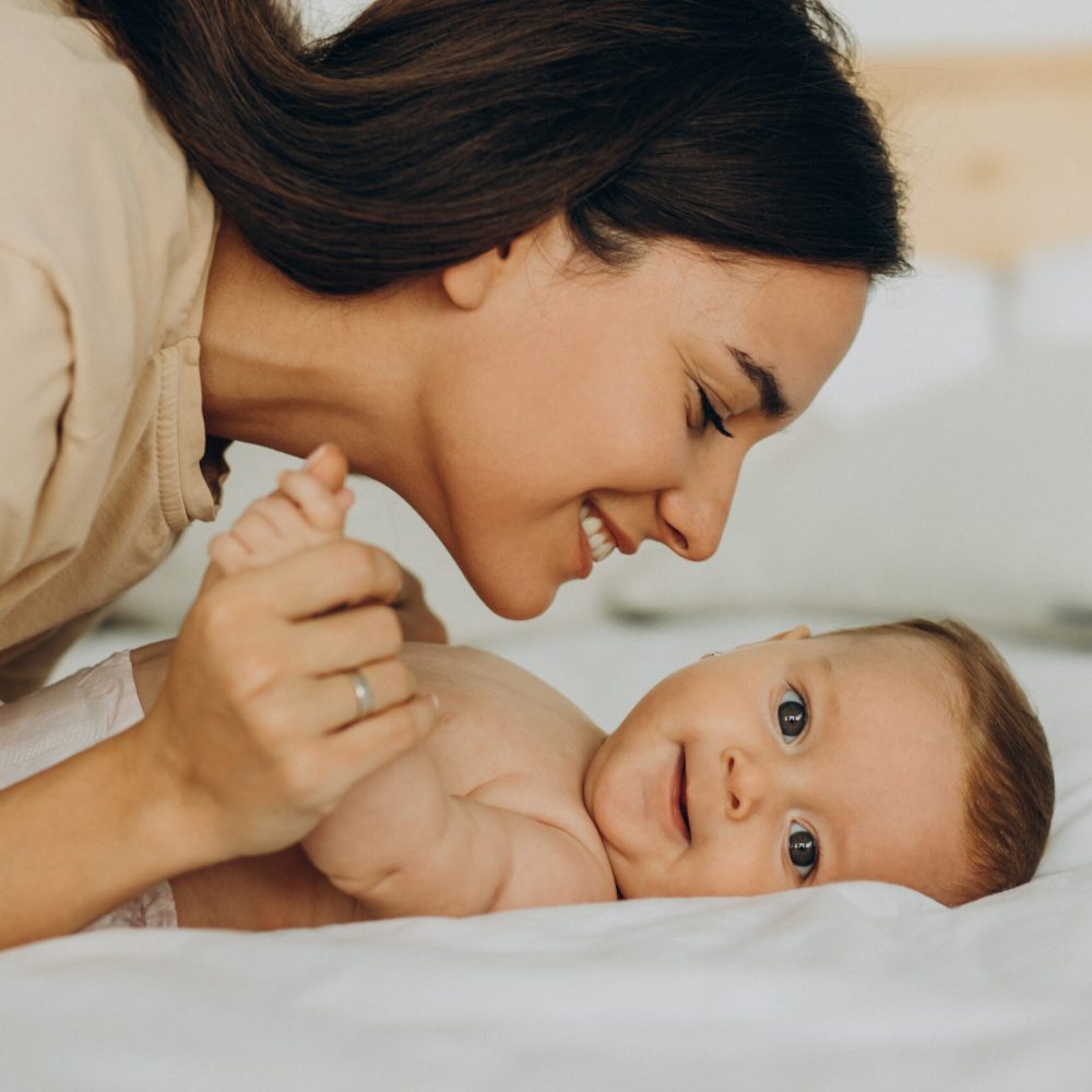 Mother with baby daughter lying on bed